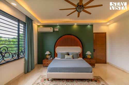 a bedroom with a large bed with a green wall at StayVista at Imperial Isle 4BHK with FREE BF Luxury Pool Villa in Sohna Delhi in Sohna