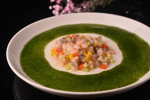 a bowl of green soup with meat and vegetables at Ocean Hotel Guangzhou - Free Shuttle Bus to Canton Fair, Tao Jin railway station in Guangzhou