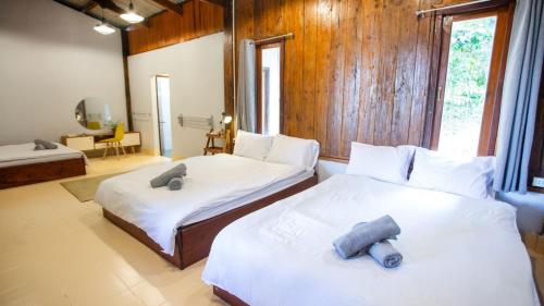 a bedroom with two beds with white sheets and wooden walls at Hug Bolaven Homestay and Camping in Ban Nongpèn