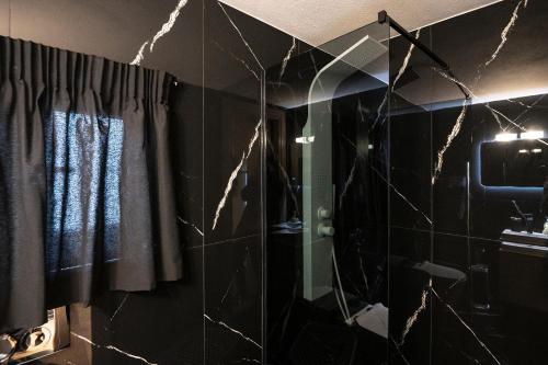 a bathroom with black tiles and a shower with a mirror at To Bee or not to Bee! in Volos