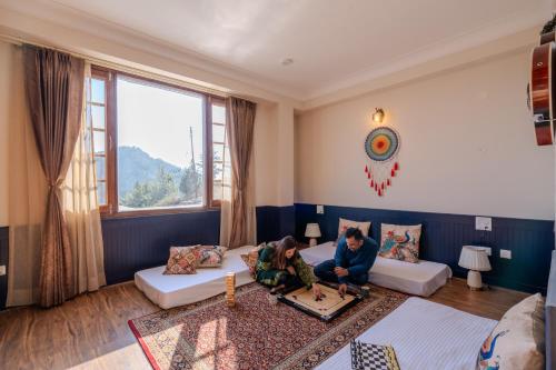 two people sitting on a couch in a living room at SaffronStays Alpine blue-6 bhk villa with private deck and valley views from each room in Shimla