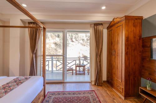 a bedroom with a bed and a sliding glass door at SaffronStays Alpine blue-6 bhk villa with private deck and valley views from each room in Shimla