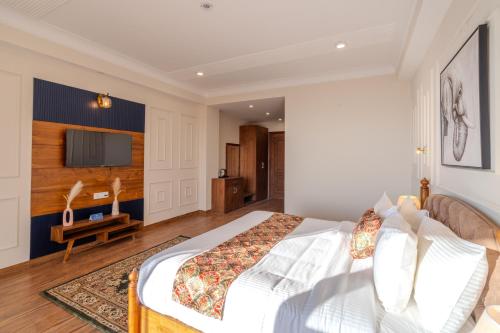 a bedroom with a large bed and a tv at SaffronStays Alpine blue-6 bhk villa with private deck and valley views from each room in Shimla