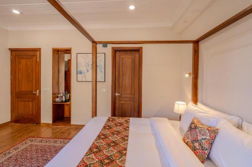 a bedroom with a white bed with a wooden headboard at SaffronStays Alpine blue-6 bhk villa with private deck and valley views from each room in Shimla