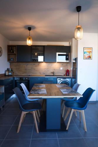 une cuisine avec une table en bois et des chaises bleues dans l'établissement Havre de paix près de Toulouse Parking inclus, à Quint-Fonsegrives