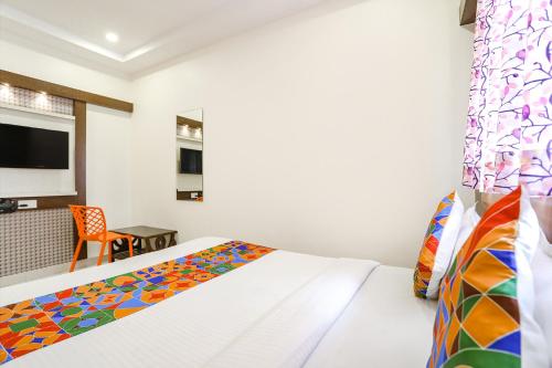 a bedroom with a bed and a chair and a tv at FabExpress Geet Residency in Mumbai