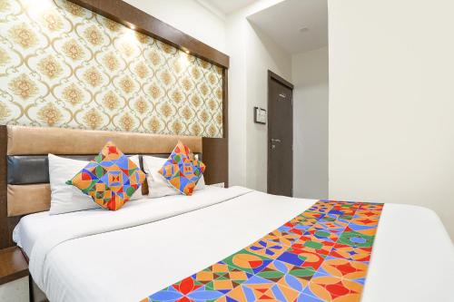a bedroom with a white bed with a colorful comforter at FabExpress Geet Residency in Mumbai