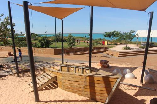 a playground with a swing and an umbrella at Guwarri Bayside Retreat in Broome