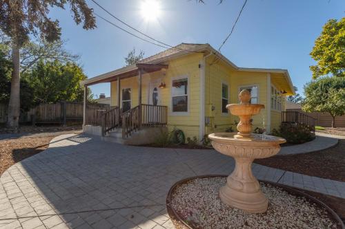 a yellow house with a fountain in front of it at Relaxing 3BR Home with Vineyard View Rooftop Deck and Game Room in Sebastopol