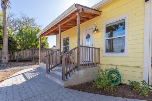a yellow house with a porch with a wooden roof at Relaxing 3BR Home with Vineyard View Rooftop Deck and Game Room in Sebastopol