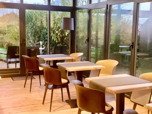 una habitación con mesas, sillas y ventanas en Hôtel Saint-Roch, Saint-Ybard, en Saint-Ybard