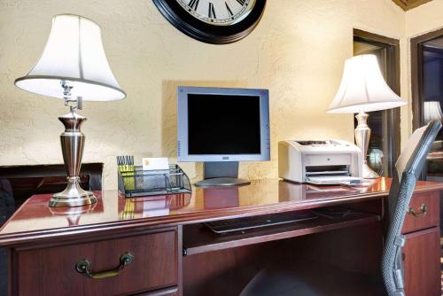 a desk with a computer and a tv and a clock at Super 8 by Wyndham Hutchinson in Hutchinson