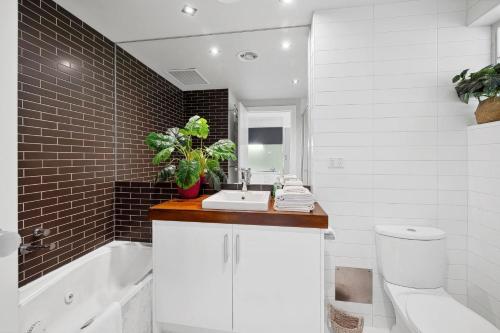 a bathroom with a sink and a toilet and a tub at Bay View Motel Number Four in Lorne