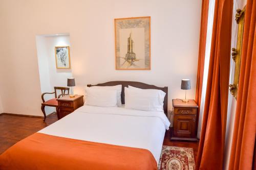 a bedroom with a bed with white sheets and an orange blanket at An der Holztreppe in Sighişoara