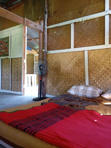 a large bed with a red blanket on top of it at Farmer house on Beverley hill Pai in Pai