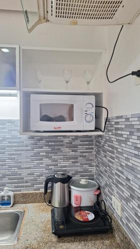 a microwave above a stove in a kitchen at Cozy Staycation in Manila