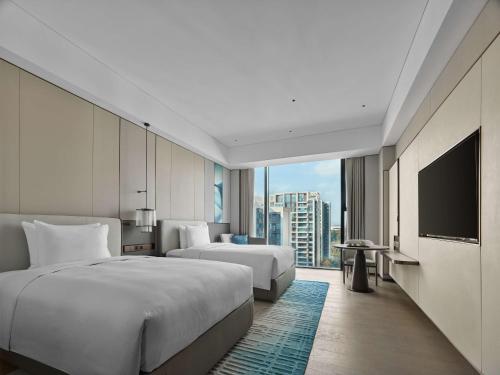 a hotel room with two beds and a flat screen tv at Doubletree By Hilton Chengdu Xinglong Lake in Chengdu