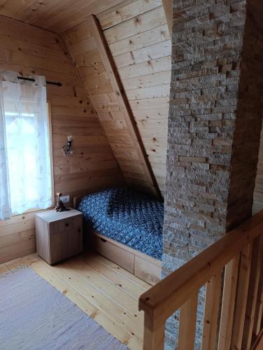 a bedroom with a bed in a wooden attic at Planinska kuća Stašević in Mitrovac