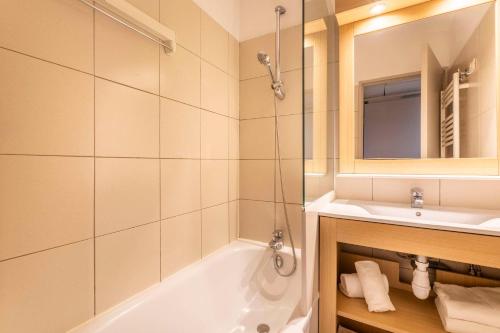 a bathroom with a tub and a sink and a mirror at Comfort Aparthotel Marseille Prado in Marseille