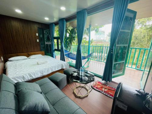 a bedroom with a couch and a bed and a balcony at Quang Minh Riverview Resort in Kroun