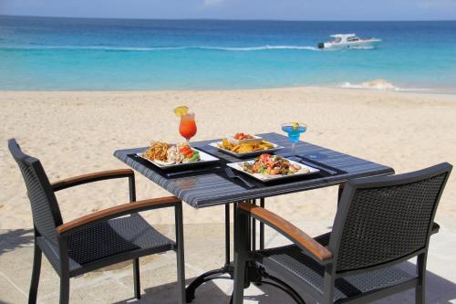a table with two plates of food on the beach at Carimar Beach Club in Meads Bay