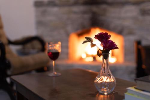 a vase of flowers and a glass of wine on a table at Lazaros Stonehouse in Pano Lefkara