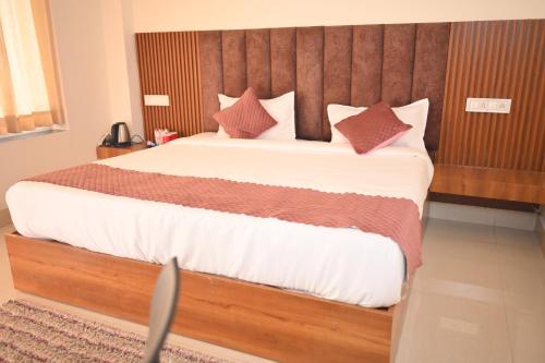 a bedroom with a large bed with a wooden headboard at Dhurva Hotel and Resort in Naugaon