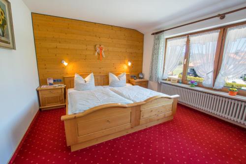 1 dormitorio con 1 cama grande y pared de madera en Haus Aigner, en Fischen