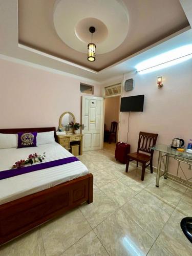 a bedroom with a bed and a desk and a television at Nhà nghỉ Nghĩa Nhân in Da Lat