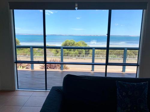 a living room with a large window with a view of the ocean at Sandcastle - A Esplanade Place, Stunning Views in Kingscote
