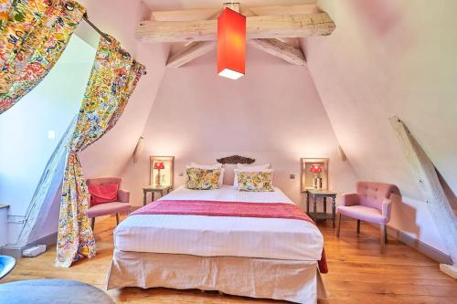 une chambre avec un grand lit et deux chaises dans l'établissement La Forge maison spacieuse 8 pers Lascaux Sarlat, à Saint-Amand-de-Coly