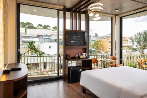 a bedroom with a bed and a television and a balcony at Phuc Hai Hotel Da Lat in Da Lat