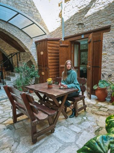 a woman sitting at a picnic table on a patio at Lazaros Stonehouse in Pano Lefkara