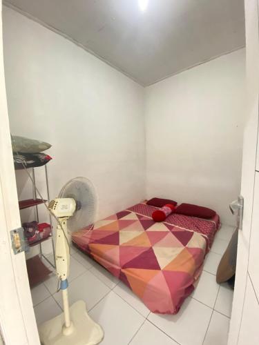 a small room with a bed and a fan at Embun Padi Homestay in Karawang