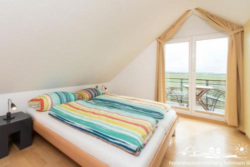 a bed with colorful blankets in a room with a window at 56 Ferienwohnung im Fritz-Bleyl-Weg 14 DG links in Burg auf Fehmarn
