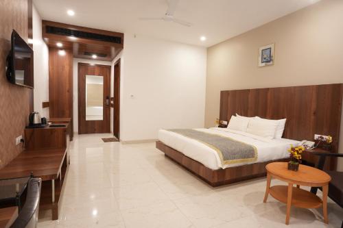 a bedroom with a bed and a table and a television at Stamps by Eight Continents, Jodhpur in Jodhpur