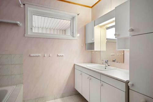 a white bathroom with a sink and a window at Flott enebolig nær naturen in Lyngen
