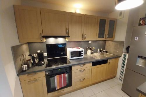 - une cuisine avec des placards en bois et un four micro-ondes dans l'établissement Charming T3 with balcony near beach, à Vannes