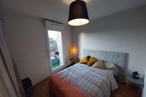 une chambre avec un lit avec une grande fenêtre dans l'établissement Charming T3 with balcony near beach, à Vannes