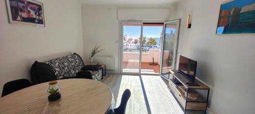 un salon avec une table et une télévision dans l'établissement Nice T2 with terrace by the sea, à Fréjus