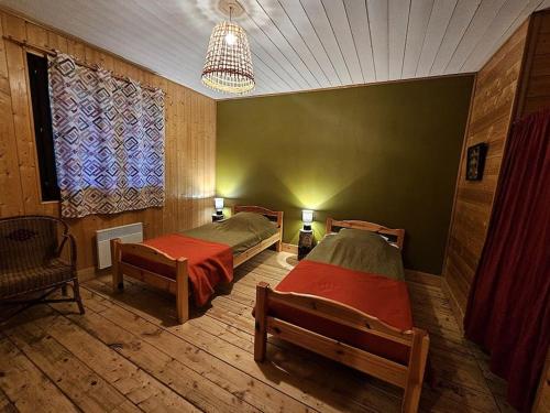 une chambre avec deux lits et un lustre dans l'établissement Le Nénuphar - Chalet avec terrasse, à Mélisey