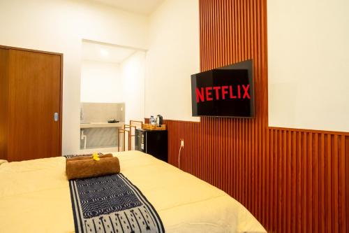 a bedroom with a bed with a netflix sign on the wall at Mesari Homestay in Sanur