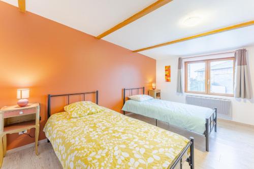 two beds in a room with an orange wall at La Promesse des Saisons - Jardin et parking privé in Cersay