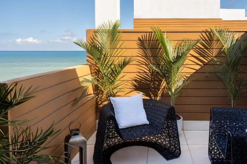a wicker chair with a white pillow sitting on a balcony at Eurostars Winter Haven Miami Beach in Miami Beach