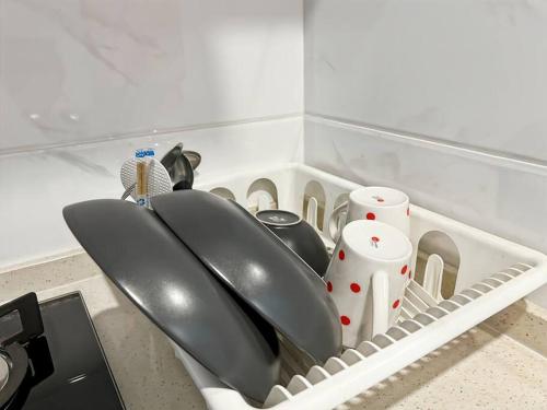 a kitchen sink with two utensils in a dish rack at Cozy Studio Skyhouse Apt near ICE BSD with pool & Gym by 2ndHome in Cilenggang