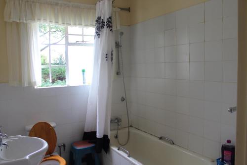 a bathroom with a tub and a toilet and a sink at Tinotenda Cottage in Harare