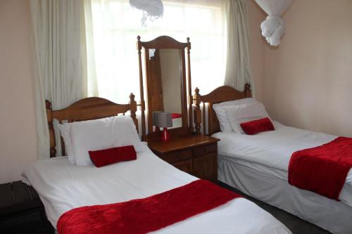 a bedroom with two beds with red and white sheets at Tinotenda Cottage in Harare