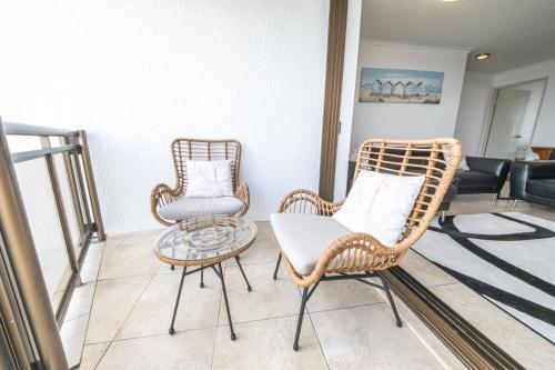 two wicker chairs and a table in a living room at Duporth - Luxury Riverfront Apartment in Maroochydore