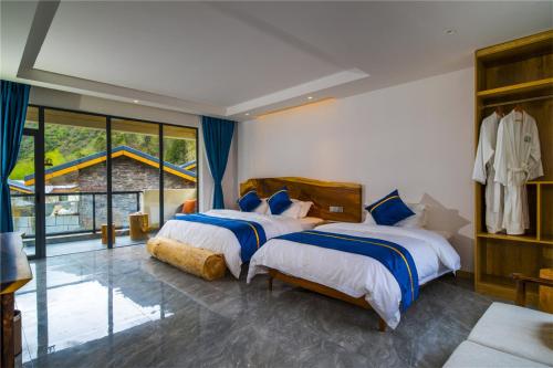 a bedroom with two beds and a large window at Summergarden Hotel in Wolongguan