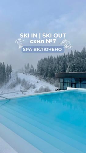 a blue swimming pool in front of a building at SAVOIE Apartments Bukovel in Bukovel